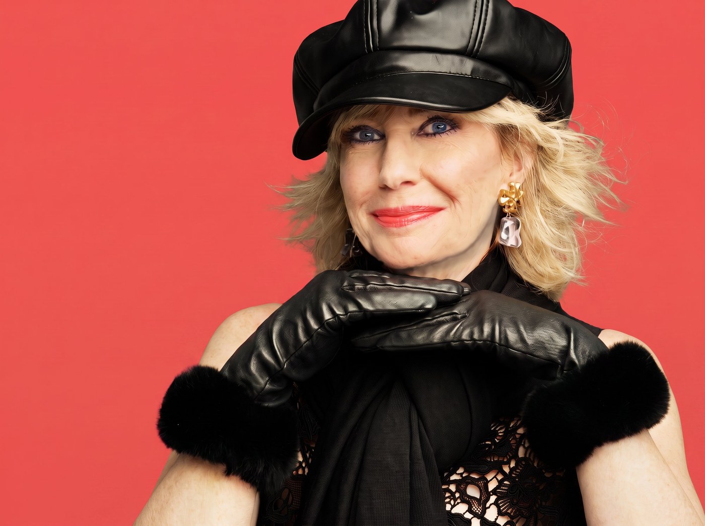 Editorial portrait &mdash; black leather cap and gloves, coral seamless, Uptown Loft.